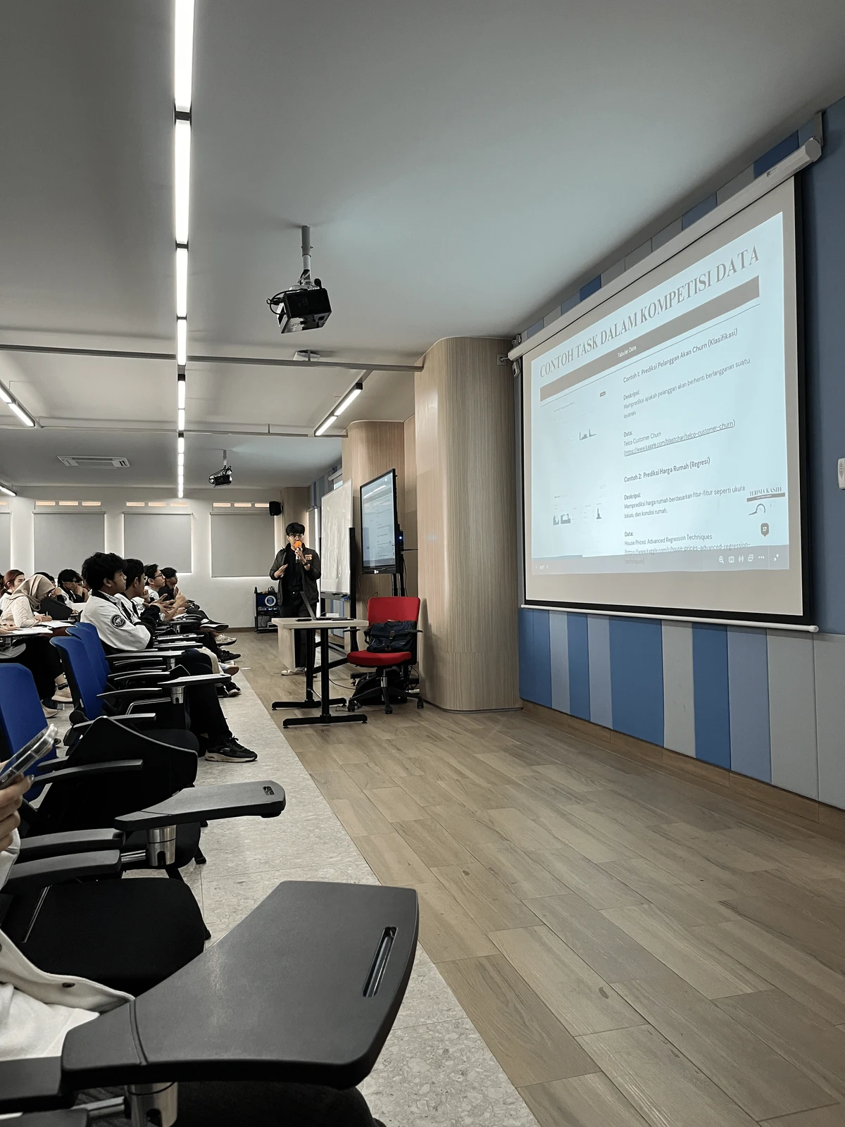 Sesi pembicara di ruang kelas dengan slide strategi kompetisi data